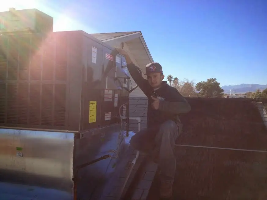 HVAC technician performing AC Tune-Up on a rooftop unit in Bakersfield